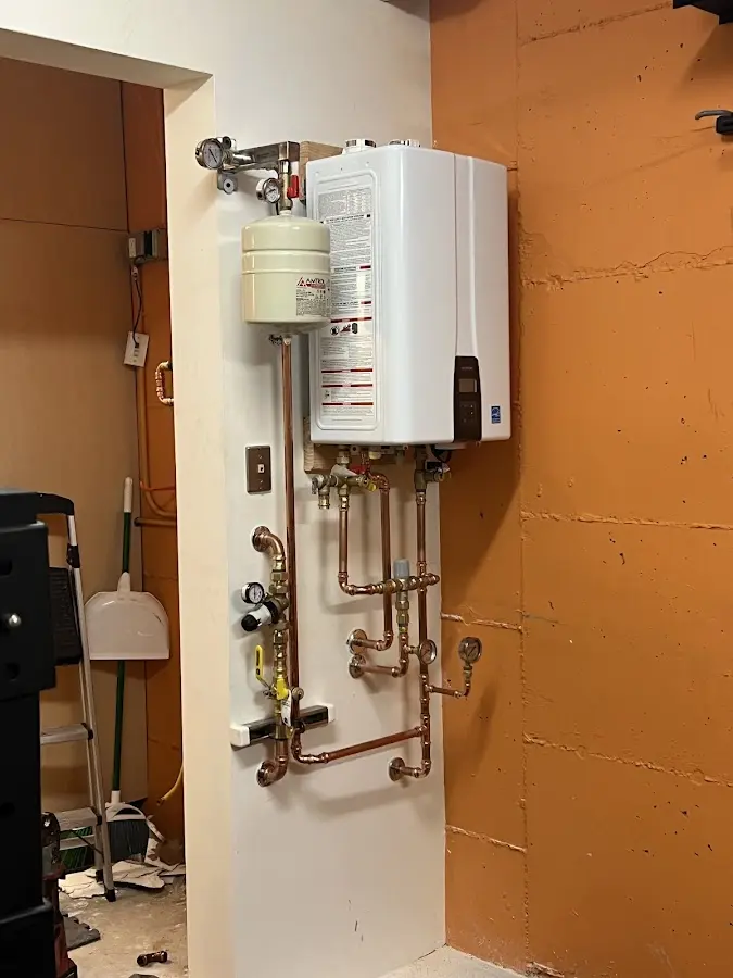Plumbing technician inspecting water heater connections in Melwood